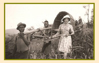 Susie Brucks standing beside the hammock carried by her African porters that she travelled in when going out into the villages in Africa. 